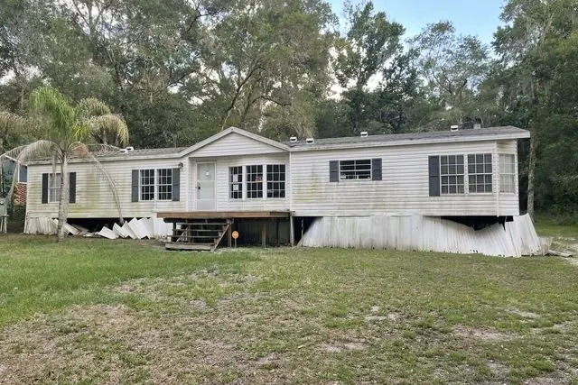 Weathered manufactured home on acreage